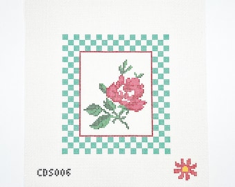 May include: Needlepoint canvas featuring a pink rose with green leaves and a red stem, framed by a red border and a teal and white checkered pattern. The canvas has the text "CDS006" and a small flower.