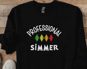 May include: Black sweatshirt featuring the text "PROFESSIONAL SIMMER" in white, with green, yellow, and red diamond shapes. The word "BLACK" is printed at the bottom. White trainers and denim jeans are visible on the sides.