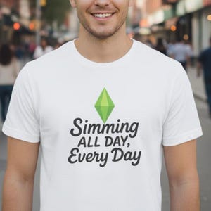 May include: White t-shirt featuring a green diamond graphic above the text "Simming ALL DAY, Every Day" in black. The shirt is made of a soft material and is suitable for casual wear.
