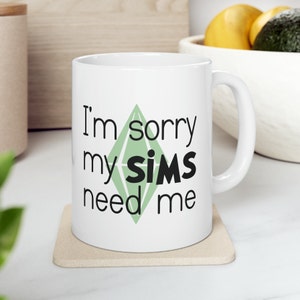 Può includere: Tazza da caffè in ceramica bianca con una grafica nera e verde di un diamante con il testo "Mi dispiace, i miei SIMS hanno bisogno di me".