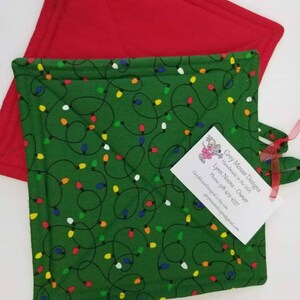 May include: Two green and red quilted pot holders with a Christmas lights pattern. The pot holders are handmade in the USA by Grey Mouse Designs. The business card includes the owner's name, phone number, and email address.