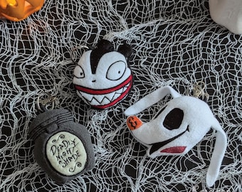 May include: Three Nightmare Before Christmas themed plush keychains. One is a black and white plush of Jack Skellington's head, another is a grey plush of a potion bottle with the text "Deadly Night Shade", and the last is a white plush of Zero the ghost dog's head.
