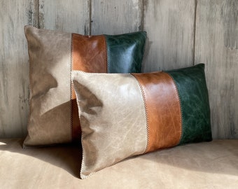 May include: Two decorative throw pillows with a striped design. The pillows are made of faux leather in shades of beige, brown, and green.
