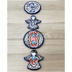 May include: Four hand-painted ceramic ornaments in a blue and white colour scheme. The ornaments feature a circular design with floral patterns, two angel figures, and a round design with a red and yellow floral pattern.