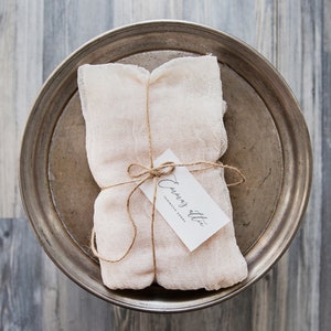 May include: A white cloth bundle tied with twine and a small white tag that reads "Envoy Attic Fantastic Goods". The bundle is sitting on a silver tray.