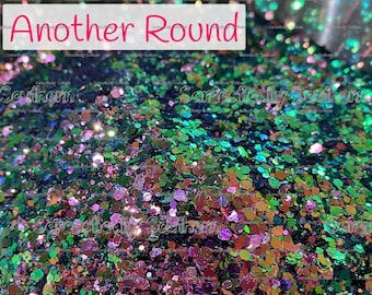 May include: A collection of loose, multi-sized hexagonal glitter particles in shades of deep emerald green, vibrant purple, and metallic copper. The text "Another Round" is printed in pink on a white rectangular overlay centered at the top.
