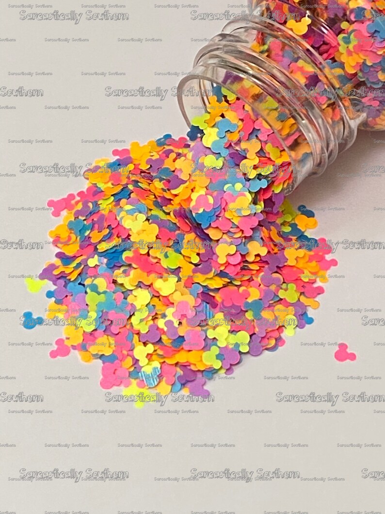 May include: A clear glass jar filled with colorful Mickey Mouse shaped confetti. The confetti is in shades of pink, blue, yellow, green, and orange.