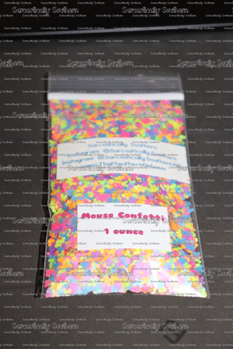 May include: A clear plastic bag filled with colorful mouse confetti. The confetti is in the shape of a mouse and is in various colors, including pink, blue, green, yellow, and orange. The bag has a label that says "Mouse Confetti 1 ounce".