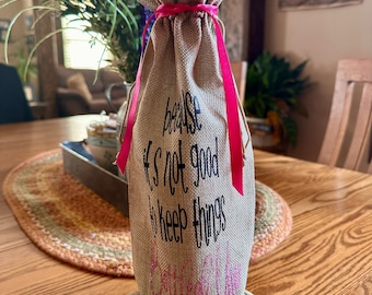 May include: A burlap wine bag with a pink ribbon and the text "because it's not good to keep things bottled up".