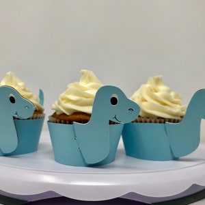 Emballages de cupcakes de dinosaure Brachiosaurus à long cou, papier cartonné bleu. Pour la baby shower ou l’anniversaire des enfants.