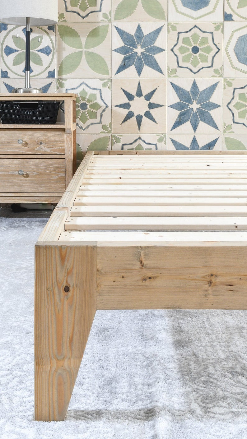 May include: A wooden bed frame with a slatted base. The frame is made of unfinished pine wood and has a simple, modern design.