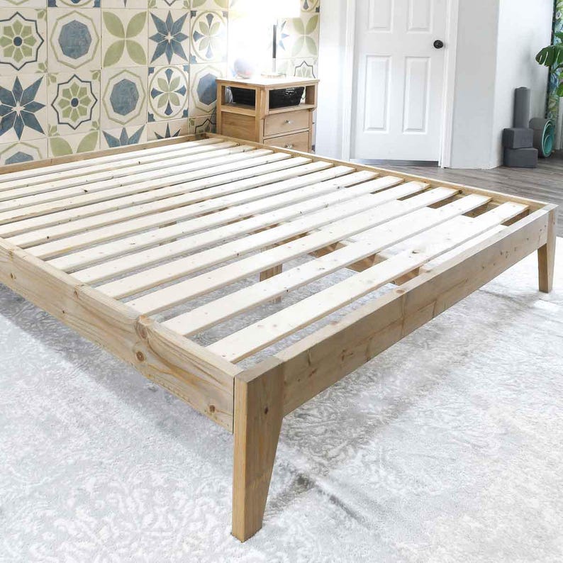 May include: A wooden bed frame with a slatted base. The frame is made of natural wood and has a simple, modern design.