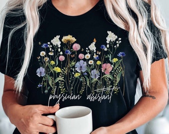May include: A black t-shirt with a floral print and the text "physician assistant" in white lettering.