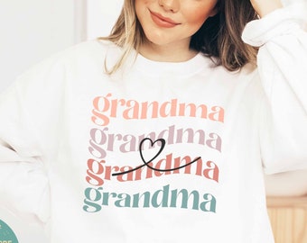 May include: White sweatshirt with the word "grandma" repeated four times in different colors and a heart symbol between the second and third words.