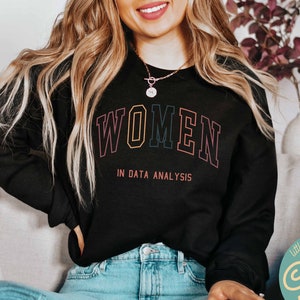 May include: Black sweatshirt with the text "WOMEN IN DATA ANALYSIS" in rainbow colors. The text is in a collegiate font style.