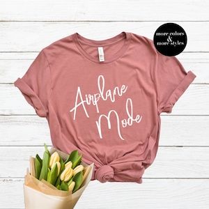 Op de afbeelding: Een mauve t-shirt met de tekst "Airplane Mode" in witte cursieve letters.