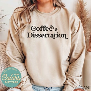 May include: A beige sweatshirt with the text "Coffee & Dissertation" printed in black.