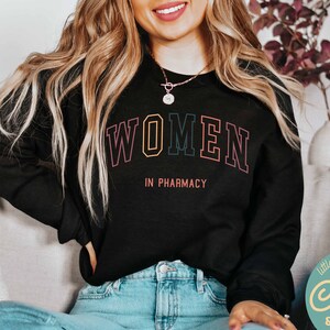 May include: Black sweatshirt with the text "WOMEN IN PHARMACY" in rainbow colored letters.