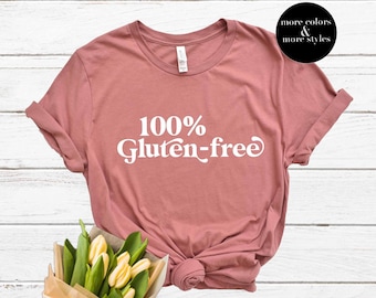 May include: A dusty rose t-shirt with the text "100% Gluten-free" in white. The shirt is made of a soft, comfortable material.