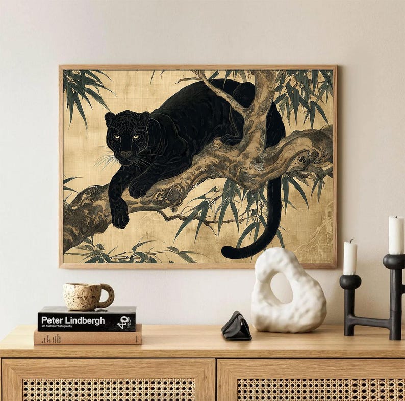 May include: A framed art print featuring a black panther resting on a tree branch. The artwork has a gold background with green foliage accents. The print is displayed on a wooden cabinet with decorative items.