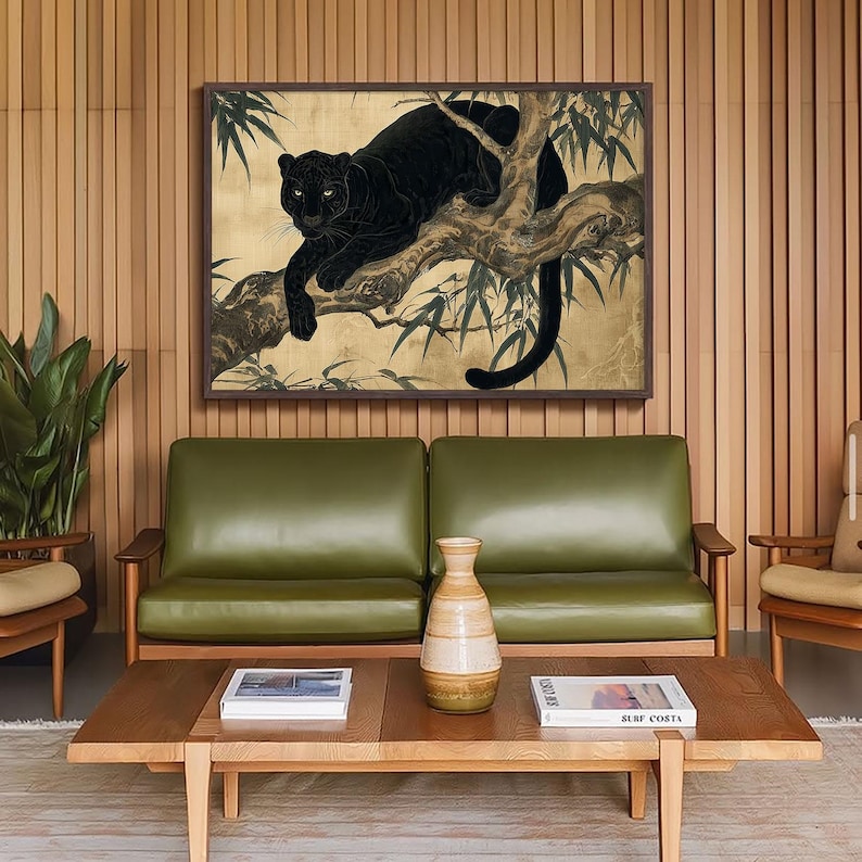 May include: A framed artwork featuring a black panther resting on a tree branch, set against a gold background with bamboo leaves. The artwork is displayed above a green leather sofa and wooden coffee table.