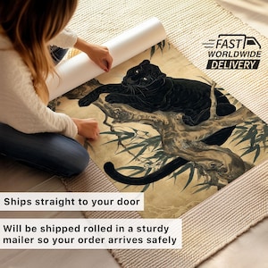 May include: A rolled art print featuring a black panther resting on a tree branch, with bamboo leaves. The artwork has a vintage aesthetic with a beige and brown color palette. The print is being unrolled on a beige rug.