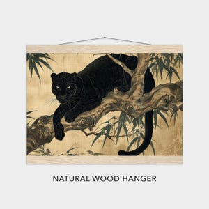May include: A black panther rests on a tree branch in this art print. The artwork is mounted on a natural wood hanger. The background is a golden color with bamboo leaves. The panther's fur is a deep black, and its eyes are focused.