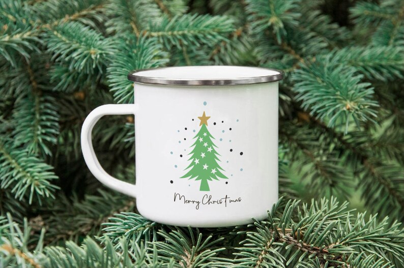 Puede incluir: Taza de esmalte blanco con un dise&ntilde;o de &aacute;rbol de Navidad verde y el texto "Merry Christmas".
