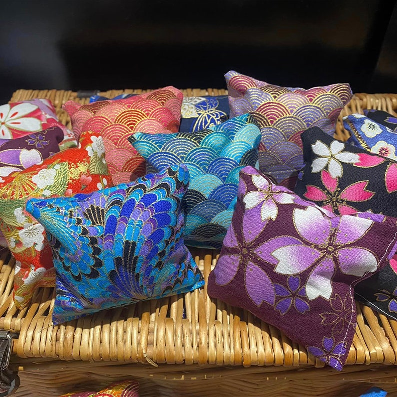 May include: An assortment of small, colourful, square cushions with various Japanese-inspired patterns. The cushions are made of fabric and have a soft, quilted texture. The patterns include floral designs, geometric shapes, and traditional Japanese motifs.