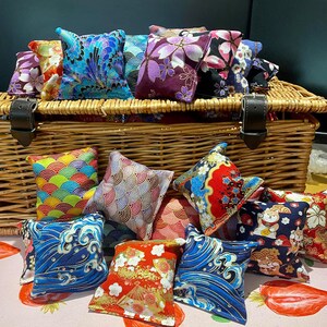 May include: A wicker basket filled with colourful fabric squares featuring Japanese-inspired patterns. The squares are arranged in a variety of designs, including floral, geometric, and wave patterns. The basket is a great way to store and display these decorative squares.