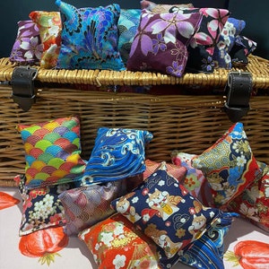 May include: A wicker basket filled with colourful Japanese-style fabric pouches. The pouches are decorated with various patterns, including flowers, waves, and geometric designs.