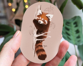 May include: A red panda sticker with a brown and white fur pattern, climbing a tree branch. The sticker is on a light brown background with a white oval border.