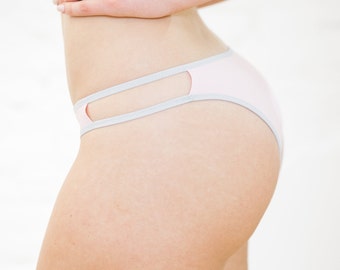 May include: Pink underwear with a gray trim and cutouts on the sides.