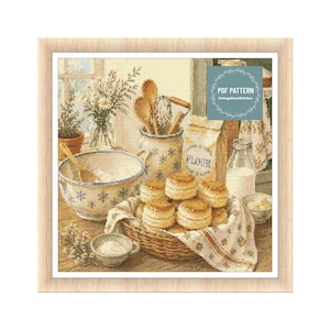 May include: A framed cross-stitch pattern showing a kitchen scene with a basket of scones on a floral cloth. Other elements include a bowl, flour, a jar of utensils, a milk bottle, and a bag of flour. The text "PDF PATTERN" is visible.