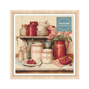 Puede incluir: Un patrón de punto de cruz que representa una escena de cocina vintage con botes rojos y blancos, una jarra y un cuenco de cerezas. El patrón está enmarcado en un marco de madera claro. El texto "PDF PATTERN CottageCoreStitches" está en la esquina superior derecha de la imagen.