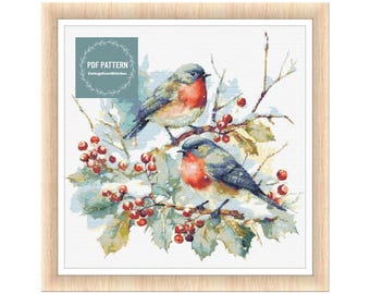 Könnte beinhalten: Gerahmtes Kreuzstichmuster mit zwei Rotkehlchen auf einem schneebedeckten Ast mit roten Beeren und grünen Blättern. Die Vögel haben rote Brust und graue Flügel. Der Text "PDF PATTERN" befindet sich oben links.