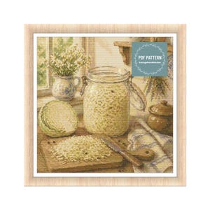Può includere: Un modello a punto croce raffigurante una scena di cucina con un barattolo di crauti, un cavolo e un tagliere con cavolo tritato. Sono visibili anche un piccolo vaso di fiori e un piccolo vaso. Il testo "PDF PATTERN" è in alto a destra.