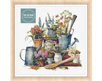 May include: A cross stitch pattern featuring a vintage-style illustration of a collection of potted plants and watering cans. The plants are in various colors, including pink, purple, orange, and green. The watering cans are blue and silver. The pattern is on a white background.