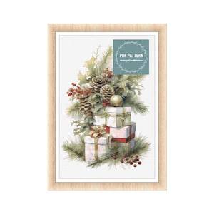 May include: A framed print featuring a festive holiday design. The artwork depicts a stack of wrapped gifts adorned with red ribbons, pine cones, and holly. The print includes the text "PDF PATTERN" and "CottageCoreStitches".