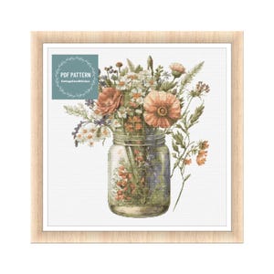 May include: A cross stitch pattern featuring a mason jar filled with a bouquet of wildflowers in shades of orange, pink, and white. The pattern is titled "PDF Pattern CottageCoreStitches".
