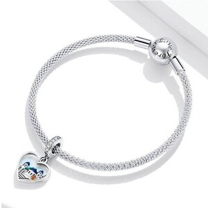 May include: A silver charm bracelet with a heart-shaped charm featuring a colorful cityscape. The bracelet has a mesh design and a clasp that reads "Love Forever".