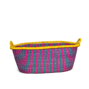 Pode incluir: Uma cesta grande, oval, tecida com um padrão listrado rosa e azul-turquesa e uma borda amarela. A cesta tem duas alças amarelas de cada lado.