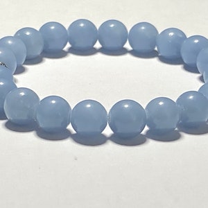 May include: A light blue beaded bracelet. The bracelet is made of round, smooth beads, strung together to form a complete circle. The beads are a soft, pastel blue color, and the bracelet appears to be made of a durable material.