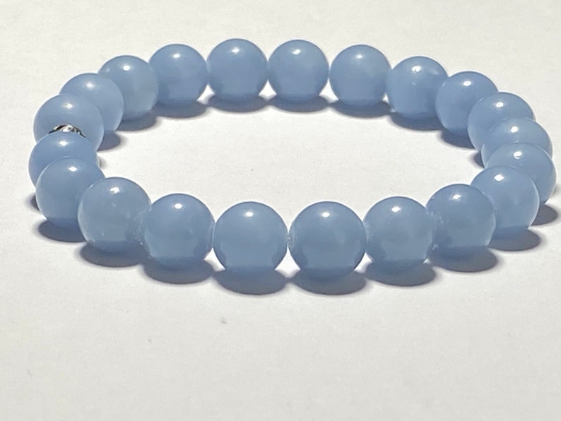 May include: A light blue beaded bracelet. The bracelet is made of round, smooth beads, strung together to form a complete circle. The beads are a soft, pastel blue color, and the bracelet appears to be made of a durable material.