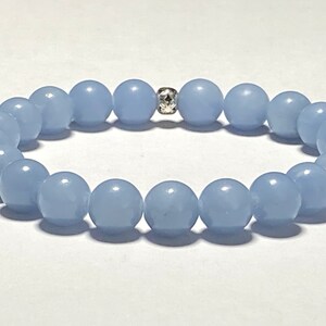 May include: A light blue beaded bracelet. The bracelet features round, smooth beads strung together with a silver-colored spacer bead. The beads are a soft, pastel blue color.