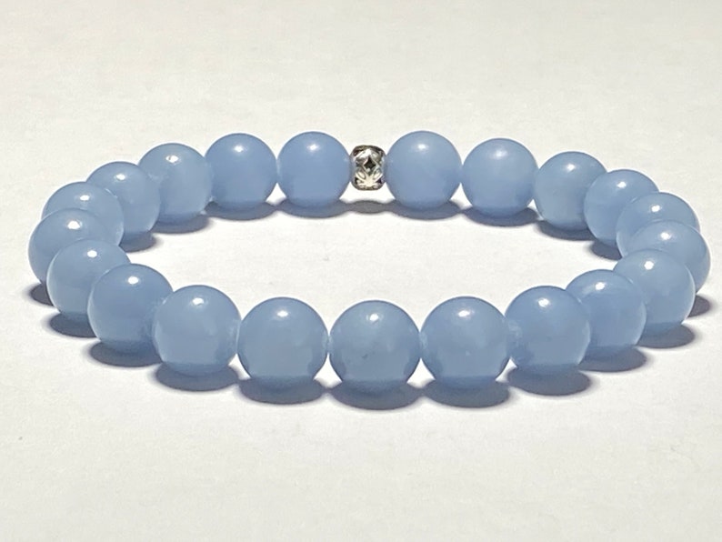 May include: A light blue beaded bracelet. The bracelet features round, smooth beads strung together with a silver-colored spacer bead. The beads are a soft, pastel blue color.
