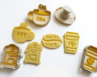 May include: A collection of yellow plastic cookie cutters in various coffee-themed shapes. Designs include coffee cups with steam, coffee beans with "PAUSE CAFE" text, and a coffee maker. Ideal for baking coffee-themed cookies.