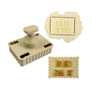 May include: A beige cookie stamp with the text "CHLOÉ 18 ANS" and a matching impression. The stamp has a square base with a scalloped edge and a handle. The text is in a gold colour.