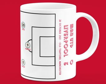 May include: White ceramic mug featuring a soccer game diagram with player numbers and names. The mug displays the score of a match between Man Utd and Liverpool, dated October 24, 2021, at Old Trafford, Manchester.