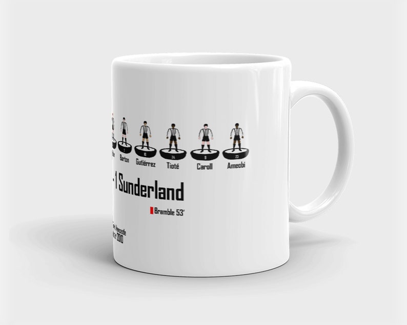 K&ouml;nnte beinhalten: Wei&szlig;e Keramiktasse mit einer Schwarzwei&szlig;illustration einer Fu&szlig;ballmannschaft. Das Team ist Sunderland und die Spieler sind Barton, Gutierrez, Tiote, Carroll und Ameobi. Der Text "Bramble 53" ist in Rot unter der Aufstellung gedruckt.